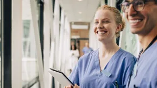 Sairaanhoitajat hymyilevät yhdessä käytävällä.
