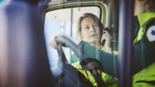 Kaksi ambulanssityöntekijää keskustelee ambulanssin ohjaamossa.